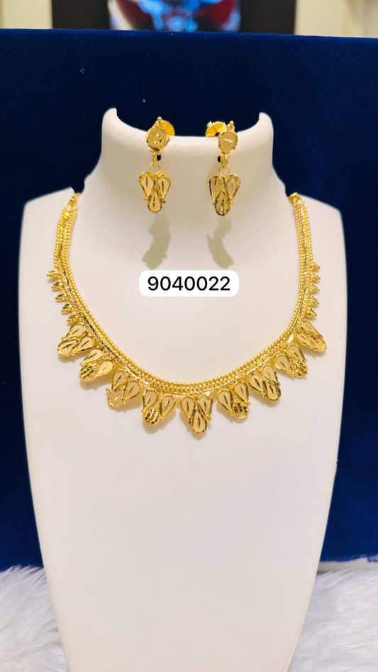 Gold necklace and earrings set on a white stand with a blue background
