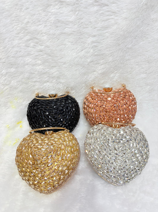 Four glittery handbags in black, gold, rose gold, and silver on a textured white background.
