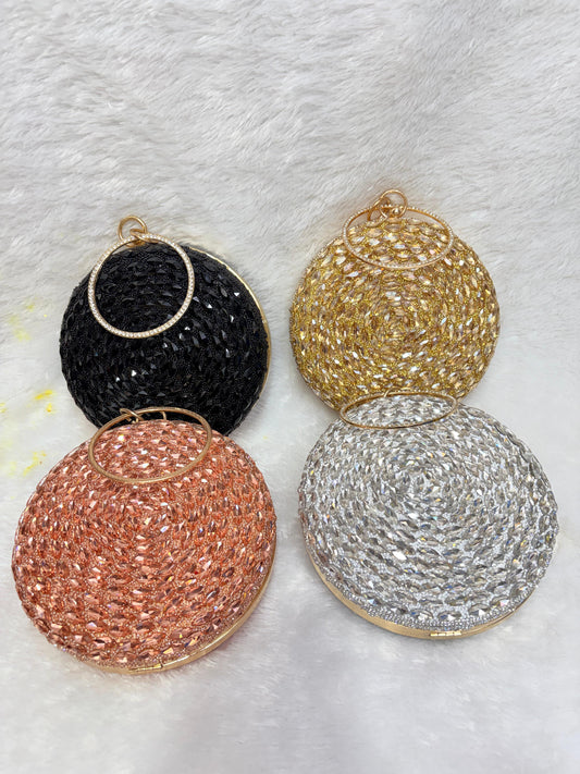 Four round, beaded clutch bags in black, gold, rose gold, and silver on a textured white background.