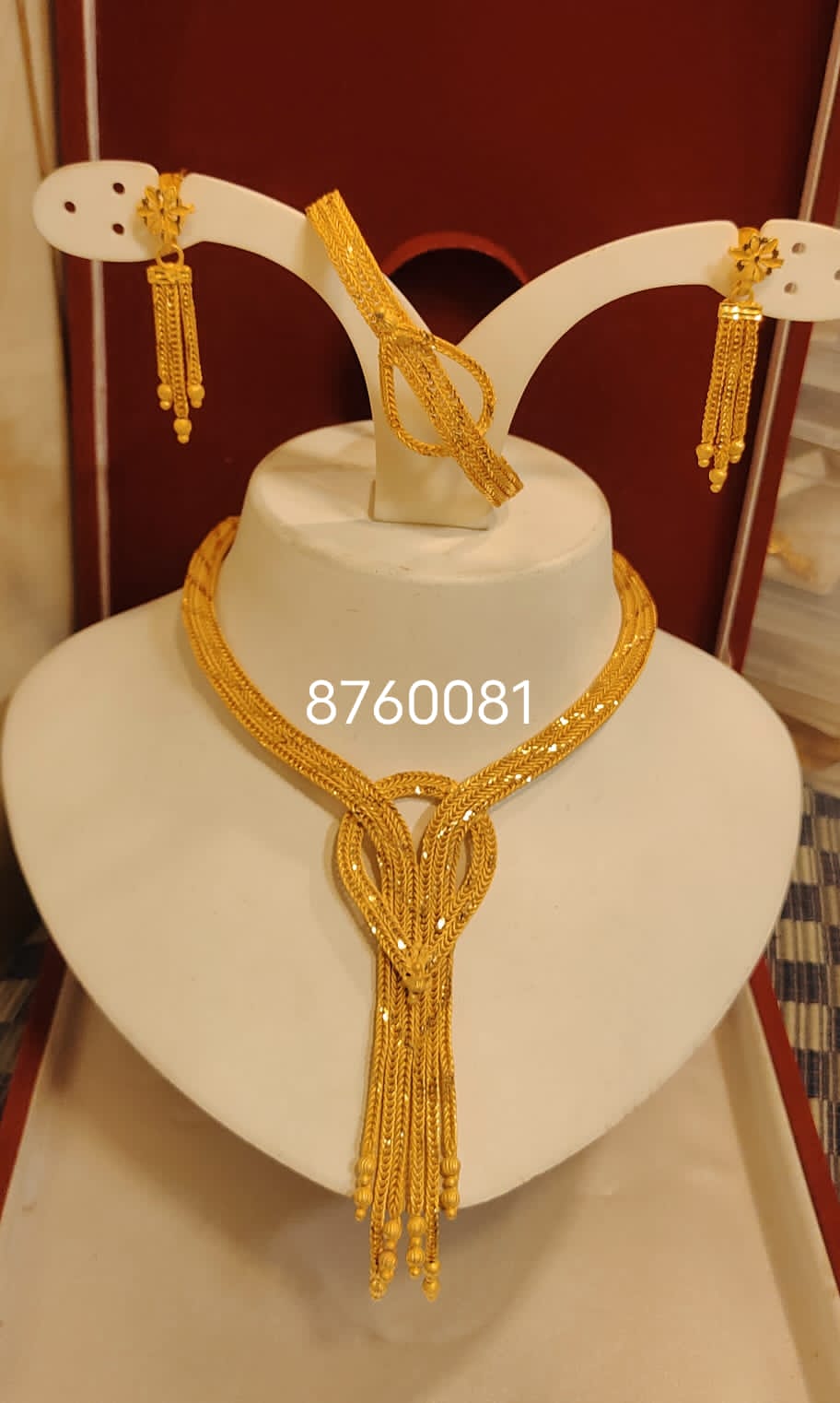 A mannequin showcasing a gold-plated necklace with a heart-shaped pendant, accompanied by a matching necklace and earrings set.